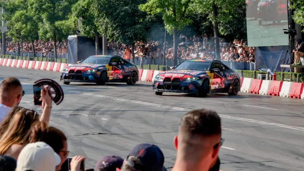 Divas sacīkšu automašīnas driftē ielās, skatītājiem vērojot notiekošo no droša attāluma.