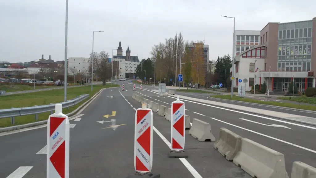 Ceļa būvdarbi ar brīdinājuma barjerām un satiksmes konusiem uz pilsētas ielas.