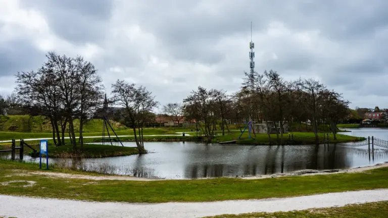 Mierpilns skats uz dīķi un atjaunoto parku ar gājēju takām Madonā.