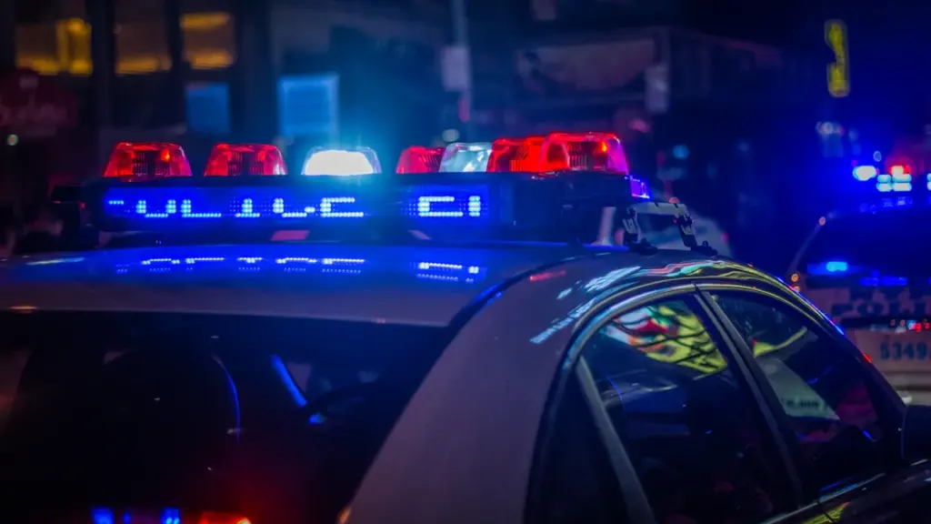 Valsts policijas automašīna ar ieslēgtām bākugunīm Rīgas ielās naktī, avārijas situācijas ilustrācija.